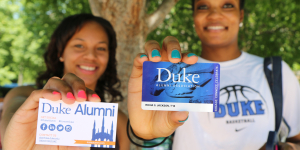 Two Duke alumni showing their alumni cards